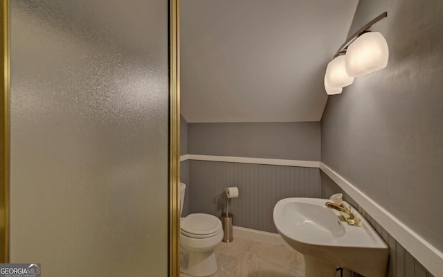 bathroom featuring lofted ceiling, sink, a shower with shower door, and toilet