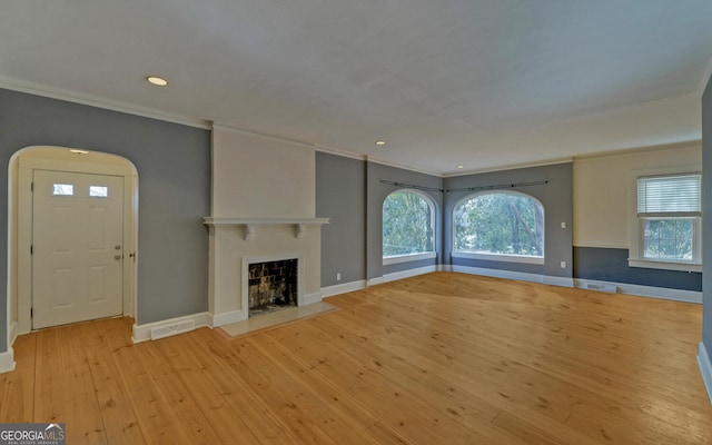 unfurnished living room with crown molding and light hardwood / wood-style floors