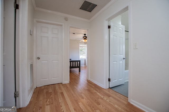 hallway with crown molding and light hardwood / wood-style flooring