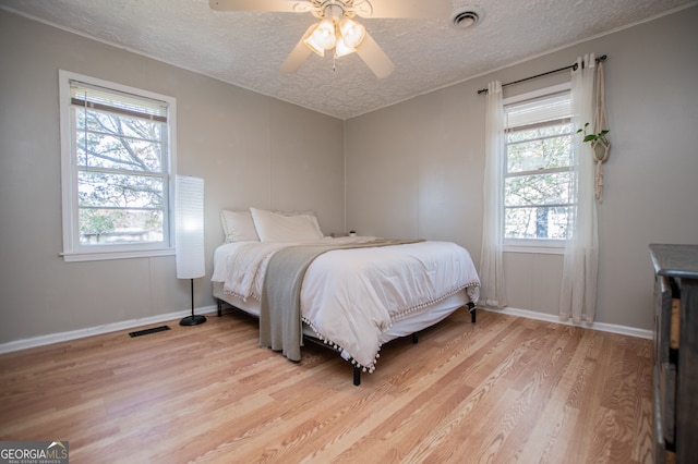 bedroom featuring ceiling fan, a textured ceiling, and light wood-type flooring