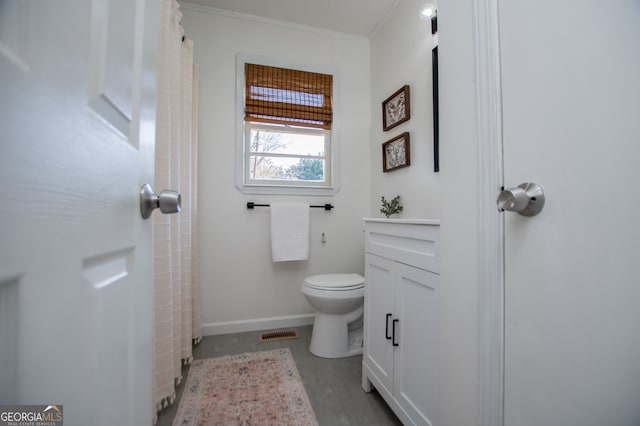 bathroom featuring hardwood / wood-style flooring, toilet, and crown molding