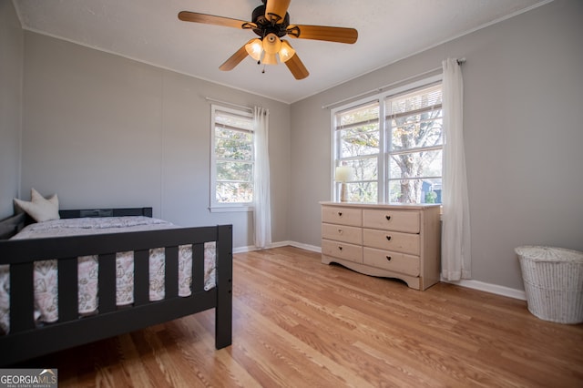 bedroom with light wood-type flooring, ceiling fan, and ornamental molding