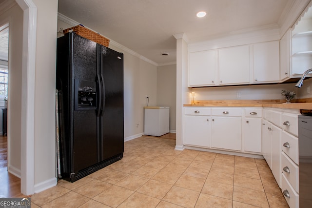 kitchen with white cabinetry, black fridge, light tile patterned flooring, and ornamental molding