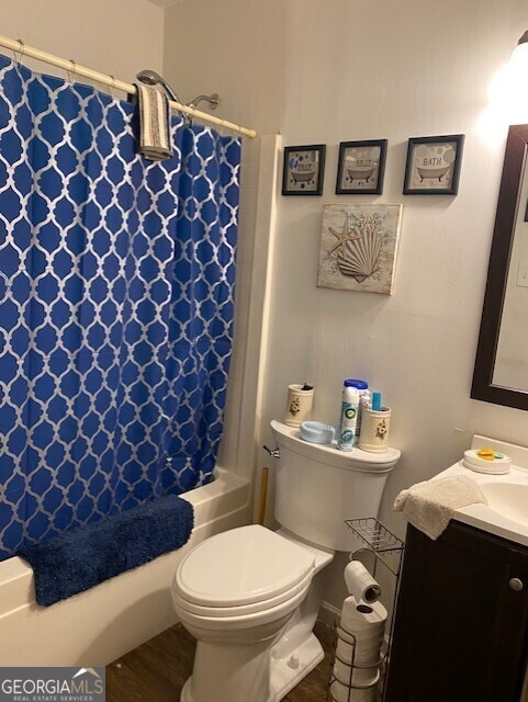 full bathroom featuring vanity, hardwood / wood-style flooring, toilet, and shower / bathtub combination with curtain