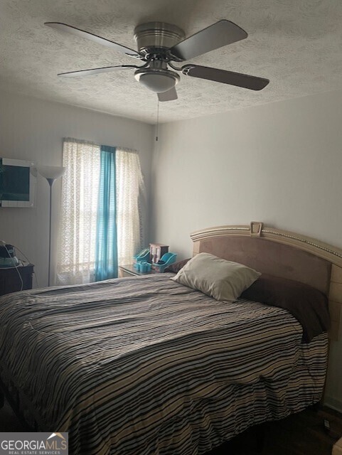 bedroom with ceiling fan and a textured ceiling