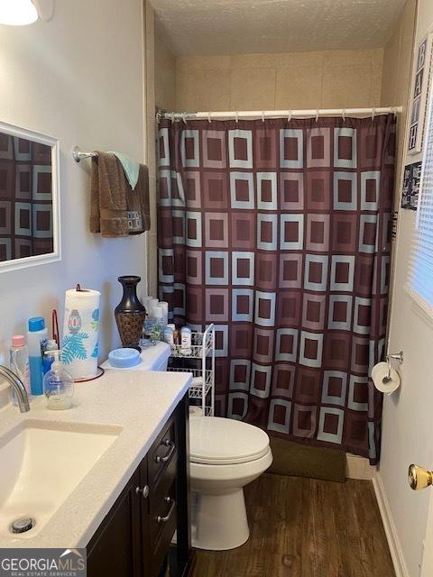 bathroom with vanity, hardwood / wood-style flooring, a shower with shower curtain, toilet, and a textured ceiling