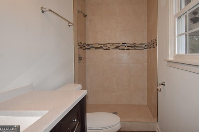 bathroom featuring vanity, toilet, and tiled shower