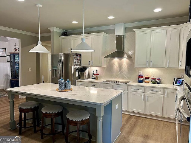 kitchen with pendant lighting, a center island, white cabinets, wall chimney exhaust hood, and stainless steel fridge with ice dispenser