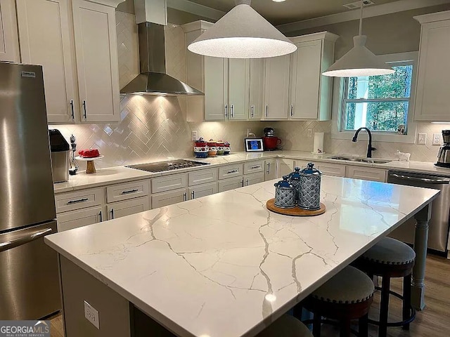 kitchen with appliances with stainless steel finishes, sink, a center island, and wall chimney range hood