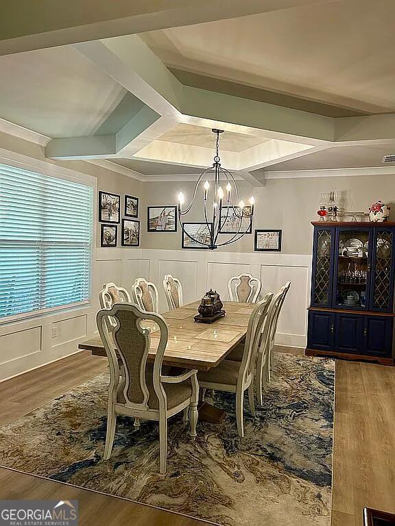 dining room with beam ceiling, wood-type flooring, and ornamental molding