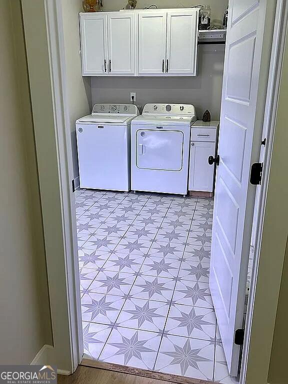 clothes washing area with cabinets and washing machine and dryer