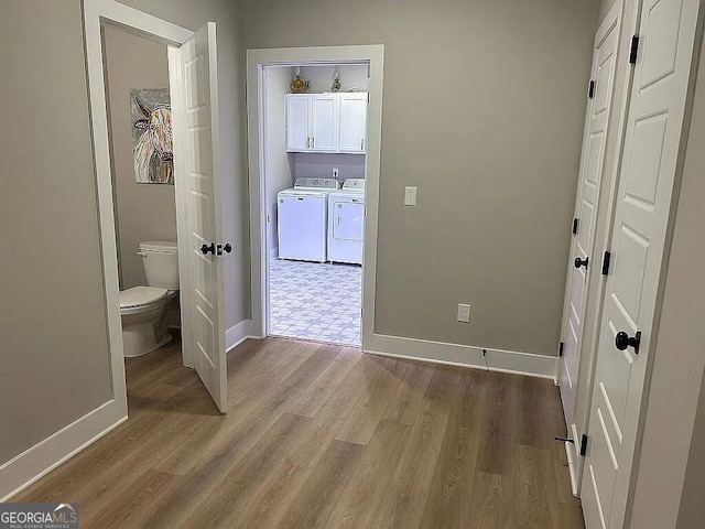 unfurnished bedroom with ensuite bath, wood-type flooring, and washing machine and clothes dryer