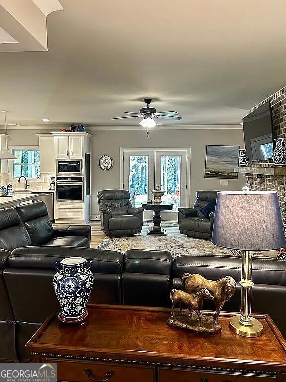 living room featuring ceiling fan, crown molding, and a wealth of natural light