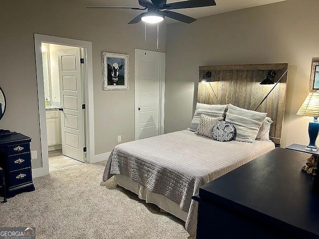 bedroom featuring connected bathroom, light colored carpet, and ceiling fan