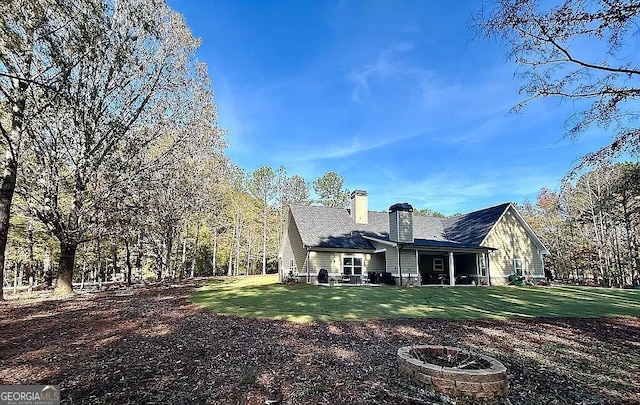 rear view of house with a yard and an outdoor fire pit