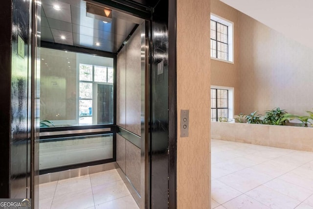 bathroom with elevator, tile patterned flooring, and a healthy amount of sunlight