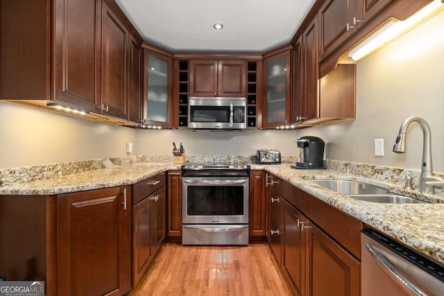 kitchen featuring light hardwood / wood-style floors, sink, light stone countertops, and stainless steel appliances