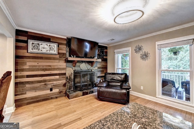 living room featuring hardwood / wood-style floors, wood walls, ornamental molding, and a fireplace