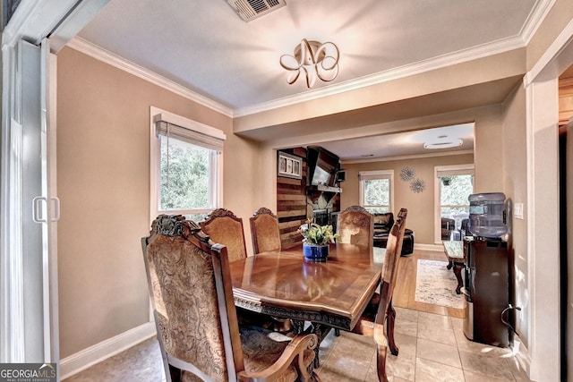 dining area with light tile patterned floors, crown molding, and a wealth of natural light