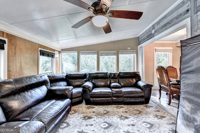 tiled living room with ceiling fan, crown molding, vaulted ceiling, and wooden walls