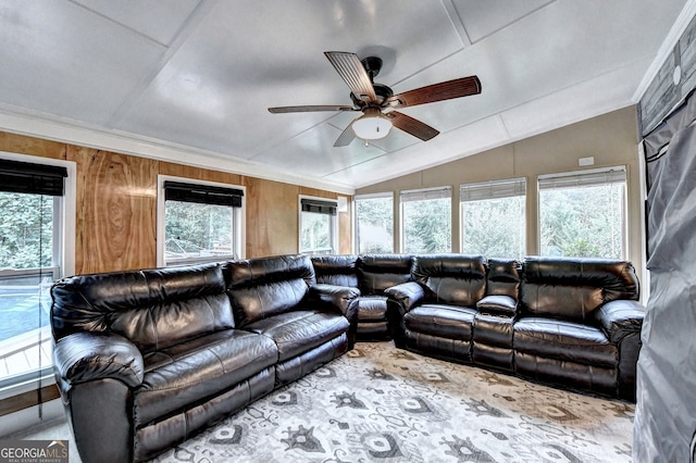 living room featuring ornamental molding, lofted ceiling, ceiling fan, and wooden walls