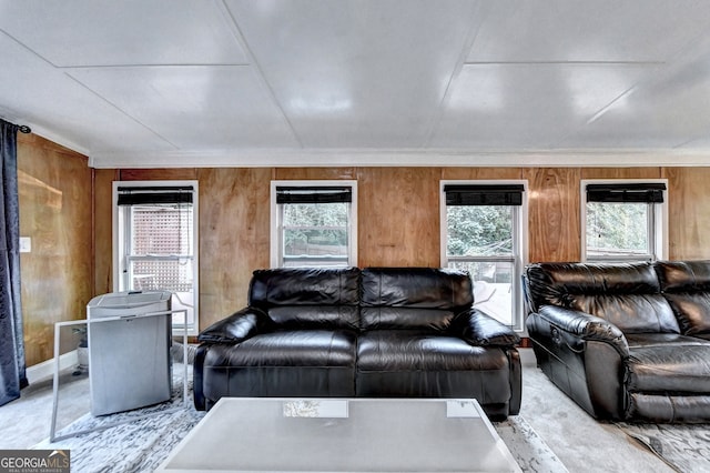 living room with a wealth of natural light, crown molding, and wood walls