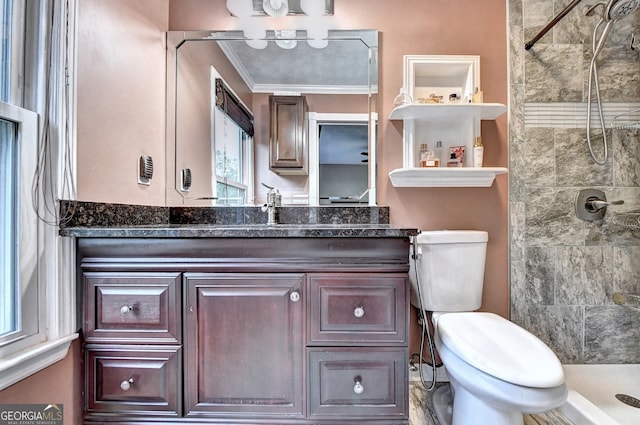 bathroom with tiled shower, vanity, toilet, and crown molding