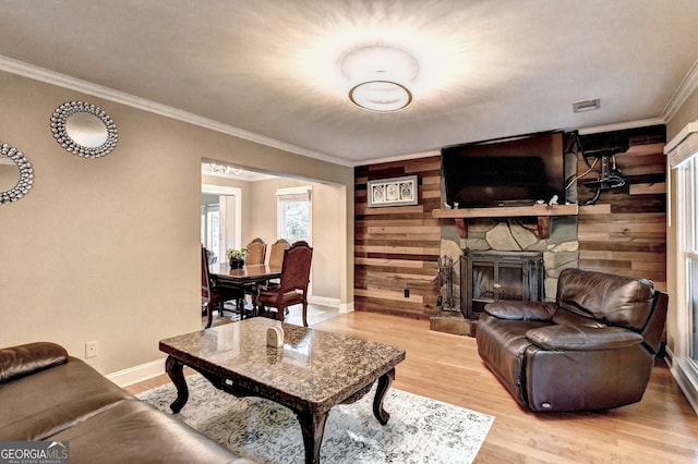 living room with a stone fireplace, wood walls, hardwood / wood-style floors, and crown molding