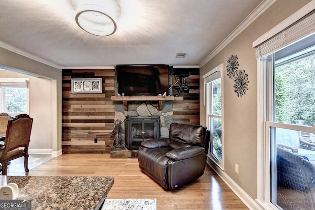 living room featuring wood-type flooring, a stone fireplace, plenty of natural light, and wooden walls