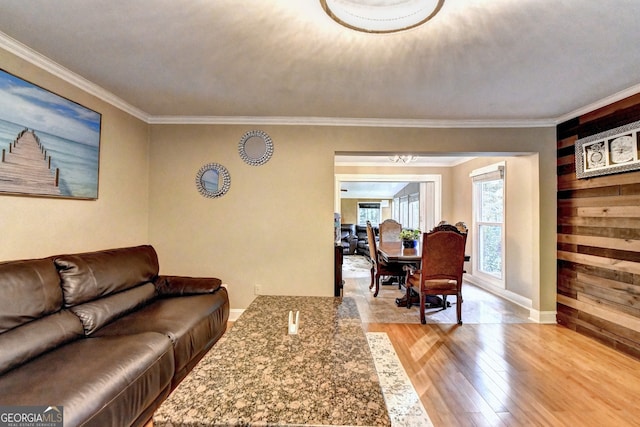 living room featuring wooden walls, light hardwood / wood-style flooring, and ornamental molding