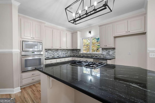 kitchen featuring pendant lighting, dark stone countertops, ornamental molding, light wood-type flooring, and stainless steel appliances