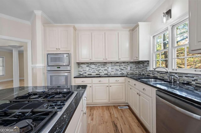 kitchen featuring white cabinets, crown molding, decorative backsplash, light hardwood / wood-style floors, and stainless steel appliances