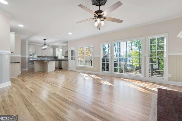 unfurnished living room with ceiling fan, light wood-type flooring, and crown molding