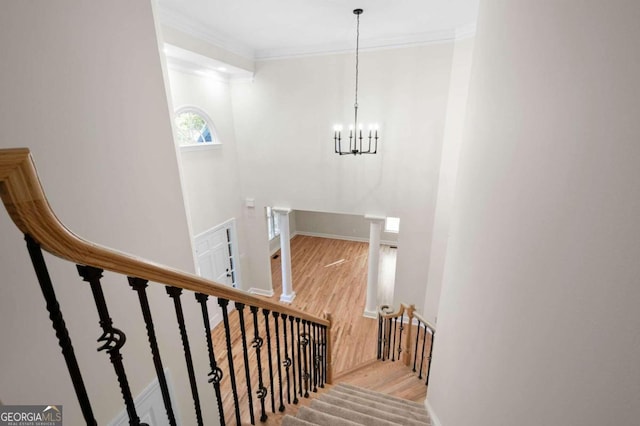 stairs with wood-type flooring, crown molding, and a notable chandelier