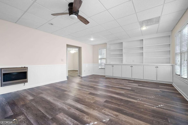 unfurnished living room featuring heating unit, dark hardwood / wood-style flooring, a healthy amount of sunlight, and built in features