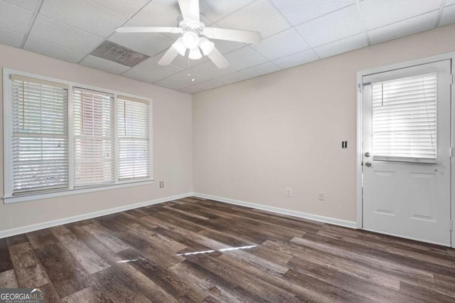 empty room featuring ceiling fan, a drop ceiling, and dark wood-type flooring