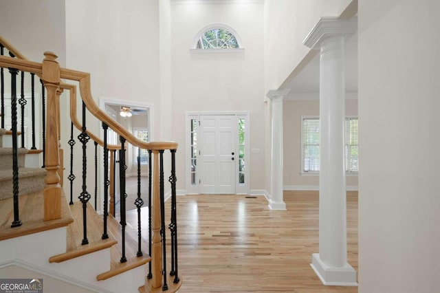 entrance foyer featuring a towering ceiling, light hardwood / wood-style floors, ceiling fan, and ornamental molding