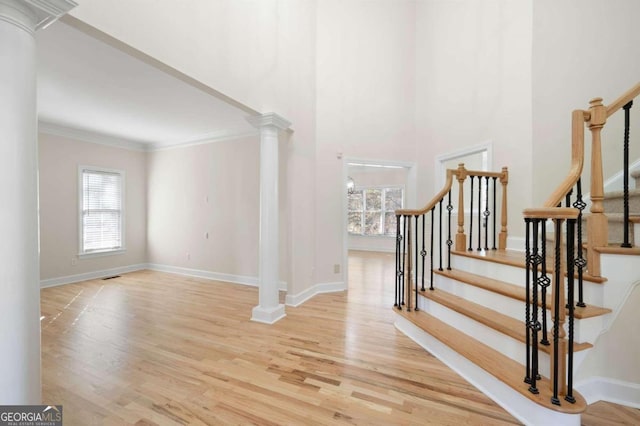 interior space with decorative columns, crown molding, and light hardwood / wood-style flooring