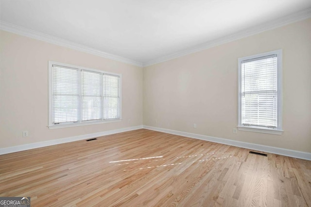 empty room with light wood-type flooring, plenty of natural light, and crown molding