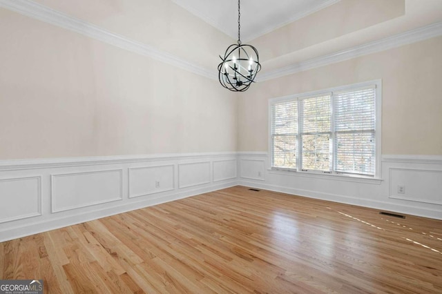 unfurnished room with an inviting chandelier, light hardwood / wood-style flooring, and crown molding