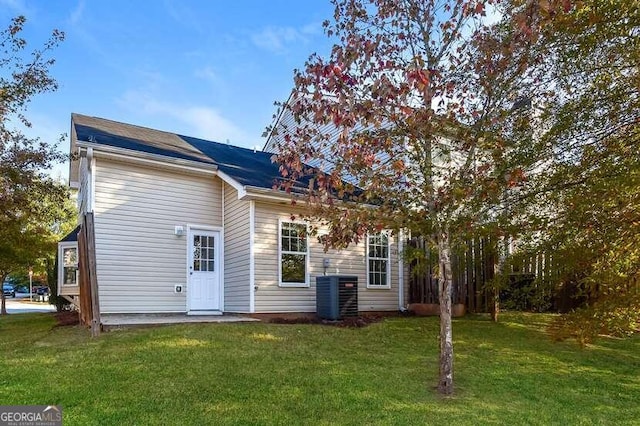 rear view of house featuring a yard and central air condition unit