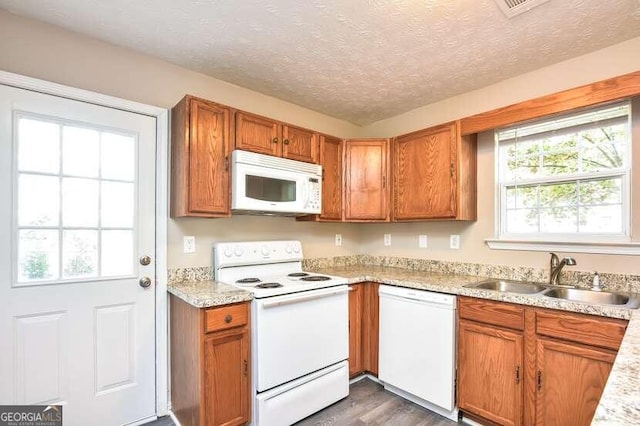 kitchen with a textured ceiling, white appliances, dark hardwood / wood-style floors, and sink