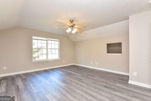 empty room featuring a textured ceiling, dark hardwood / wood-style flooring, ceiling fan, and lofted ceiling