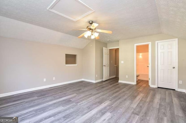 interior space featuring a textured ceiling, ceiling fan, dark wood-type flooring, and vaulted ceiling