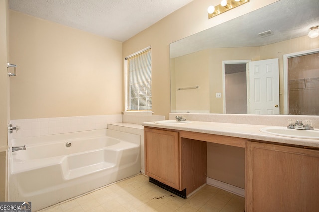 bathroom featuring a tub, vanity, and a textured ceiling