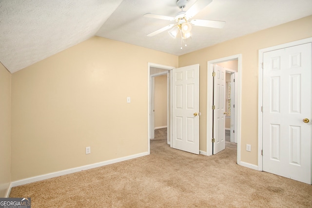 unfurnished bedroom featuring a textured ceiling, ceiling fan, light colored carpet, and vaulted ceiling