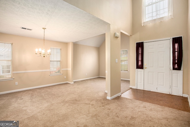 foyer with a textured ceiling, plenty of natural light, and light carpet