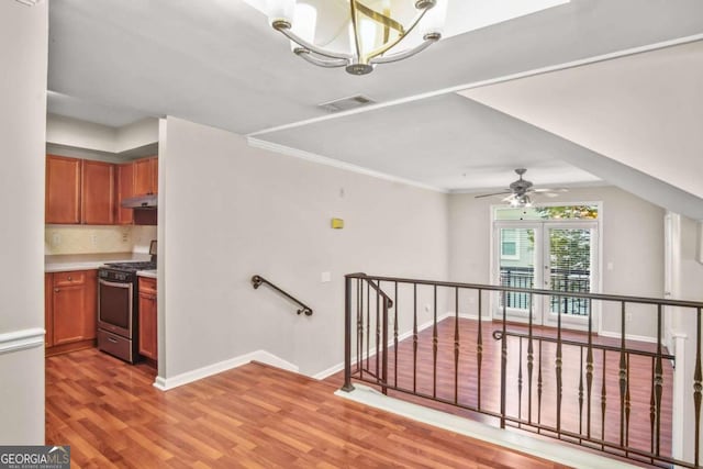 staircase with hardwood / wood-style floors and ceiling fan with notable chandelier