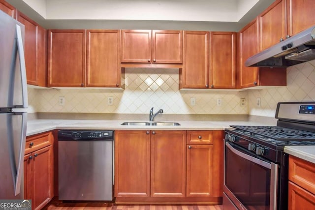 kitchen featuring light wood-type flooring, appliances with stainless steel finishes, backsplash, and sink