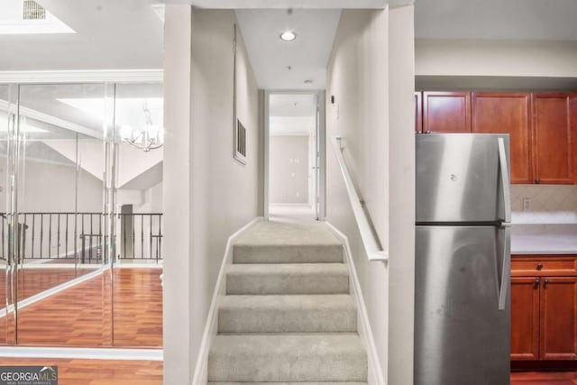 stairs with hardwood / wood-style floors and an inviting chandelier